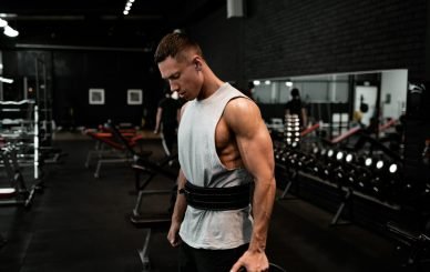 man in white tank top holding bumper plate