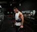 man in white tank top holding bumper plate